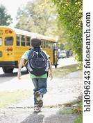 Caucasian boy running after school bus
