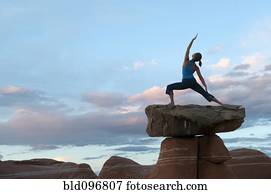 Caucasian woman practicing yoga on top of rock formation