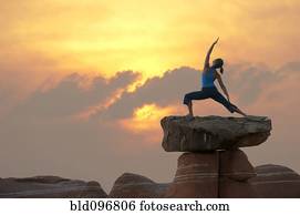 Caucasian woman practicing yoga on top of rock formation
