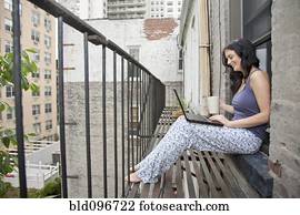 Woman using laptop on fire escape