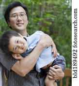 Asian father carrying son