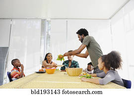 Black family eating salad at dining room table