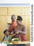 Black family preparing salad in kitchen