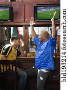 Cheering men watching television in sports bar