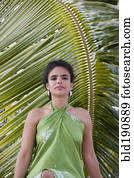 Hispanic woman in sarong near palm leaf