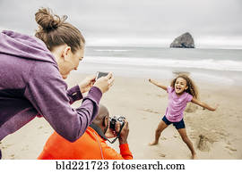 Parents photographing daughter on beach