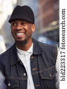 Smiling African American man wearing hat and denim vest