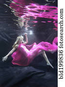 Caucasian woman in dress swimming under water