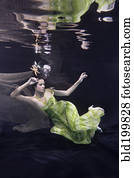 Mixed race woman in dress swimming under water