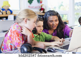 Teacher helping students using laptop