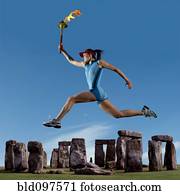 Athlete running with Olympic torch near Stonehenge