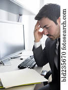 Businessman with headache at office desk