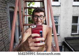Caucasian man on urban fire escape posing for cell phone selfie