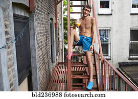 Caucasian man sitting on urban fire escape drinking orange juice