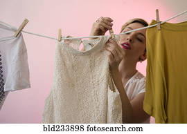Caucasian woman hanging shirts on clothesline with clothespins