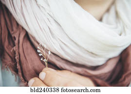 Caucasian woman holding delicate leaf near scarf