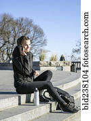 Caucasian woman sitting on staircase talking on cell phone