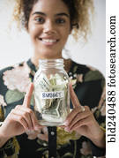 Mixed Race woman holding jar of budget money