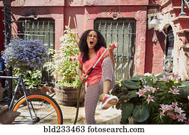 Mixed Race woman singing and playing air guitar in garden