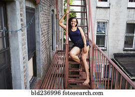 Portrait of smiling woman sitting on urban fire escape