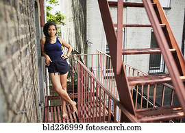 Portrait of smiling woman standing on urban fire escape