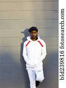 Serious Black man leaning on gray wall