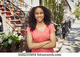 Smiling Mixed Race woman posing on city sidewalk