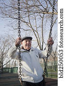 Carefree Hispanic man on swing in park