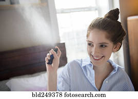 Caucasian woman spraying perfume in air