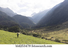 Distant carefree person walking on hill near mountains