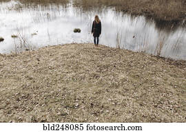 Distant Middle Eastern woman standing near pond