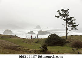 Distant people walking near foggy ocean