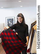 Hispanic woman examining plaid vest in store