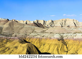 Layered rock formations under blue sky, Badlands National Park, South Dakota, United States