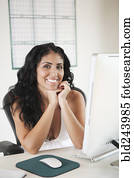 Portrait of smiling Mixed Race woman sitting at desk with computer