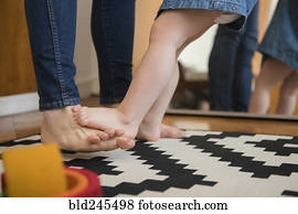 Reflection in mirror of barefoot Caucasian mother and daughter
