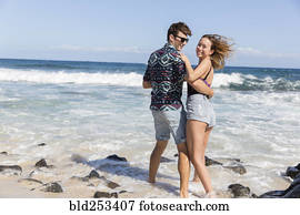 sorrindo, par abraçando, ligado, ventoso, praia