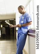 Black doctor looking at medical chart in hospital