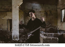 Caucasian man playing guitar in rubble