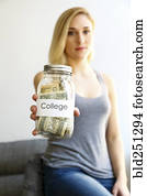 Caucasian woman showing jar of money for college Caucasian woman showing jar of money for college