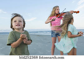 caucasiano, menina, jogando violino, ligado, ventoso, praia, perto, irmão irmã