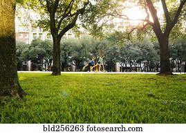 Distant Caucasian girls riding scooter in park
