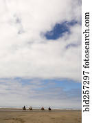 Distant people riding horses on beach