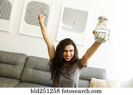 Mixed race woman on sofa celebrating with college money Mixed race woman on sofa celebrating with college money