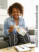 Mixed race woman saving money in jar for college Mixed race woman saving money in jar for college