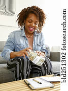 Mixed race woman screw lid on jar of money for college Mixed race woman screw lid on jar of money for college