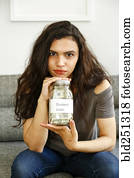 Portrait of mixed race woman holding jar of money for student loan