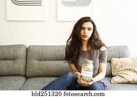 Portrait of mixed race woman holding jar of money for college Portrait of mixed race woman holding jar of money for college