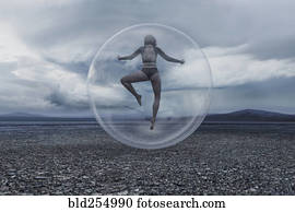 Woman floating in sphere in remote landscape