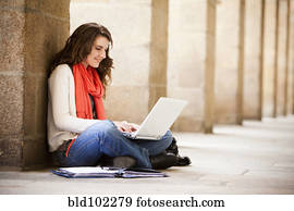 Caucasian woman sitting on ground with laptop
